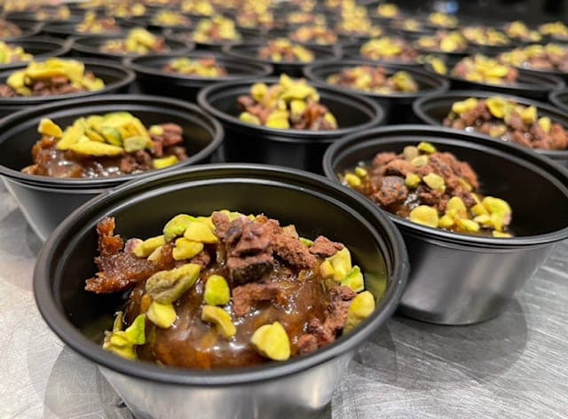 Rows of prepared trays with small dark bites and grains