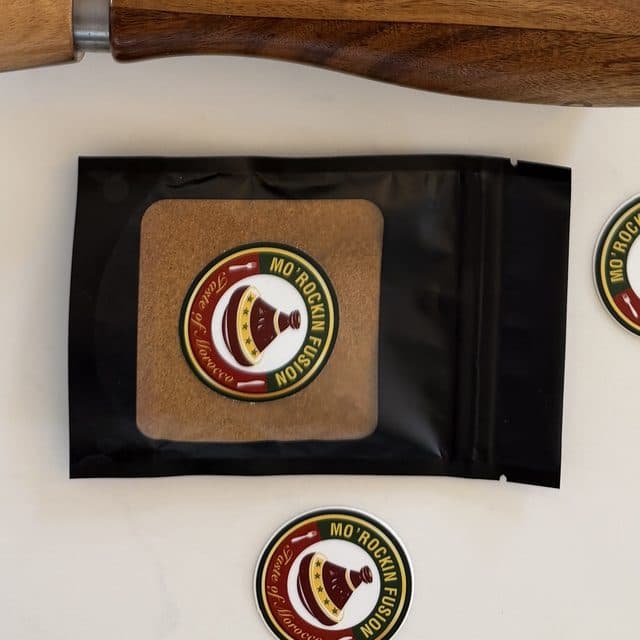 A black zip pouch of ground spice with a round Mo'Rockin Fusion label, on white marble